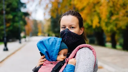 donna con mascherina e bambino in braccio