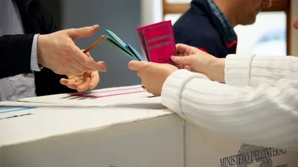 Una persona consegna la scheda elettorale dopo aver votato