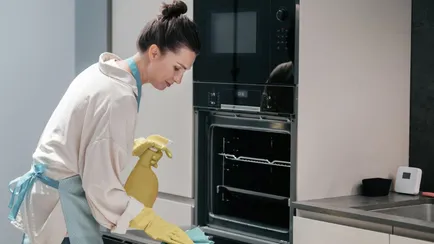 donna con guanti e detersivo pulisce il forno di casa