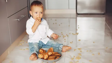 bambino in cucina mangia cibo sul pavimento