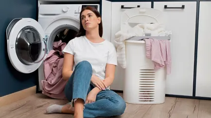 donna sconsolata tra bucato e lavatrice